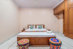 a bedroom with a bed and two stools at FabHotel Pink Cozzy in Jaipur