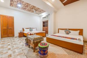 a bedroom with two beds and a table in it at FabHotel Pink Cozzy in Jaipur