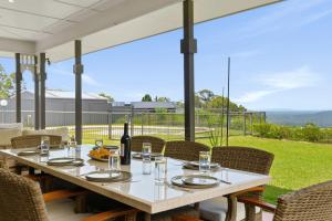 einen Tisch mit einer Flasche Wein und Stühlen auf einer Terrasse in der Unterkunft Coastview Manor - Family Hinterland Retreat in Valdora