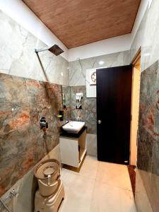 a bathroom with a toilet and a black door at Hotel Pratyaksh Darshan in Varanasi