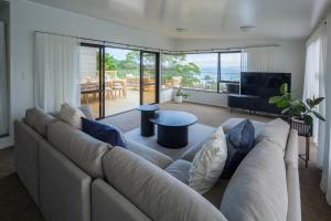 a living room with a large couch and a table at Seaviews and a stroll to Whanagaumu bay in Whangarei