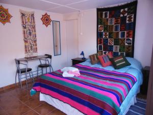 1 dormitorio con 1 cama con una manta colorida en Hostal Campo Base, en San Pedro de Atacama