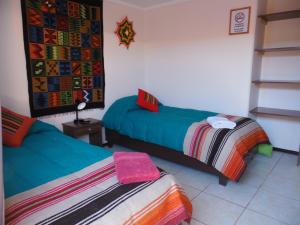 a bedroom with a bed, a desk and a painting on the wall at Hostal Campo Base in San Pedro de Atacama