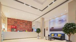 a lobby with a blue couch and a brick wall at JTOUR Inn Xiantao Shopping Mall Pedestrian Street in Xiantao