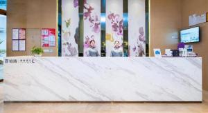 un grand comptoir en marbre dans un hall avec deux personnes dans l'établissement Lavande Hotel Lu County High-Speed Railway Station Wanhu Daduhui, à Luzhou