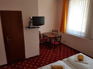 a hotel room with a table and a television at Hotel - Restaurant Sophienaue in Eisenach
