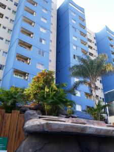 un edificio azul con palmeras delante en Golden Dolphin Roberto Imóveis, en Caldas Novas