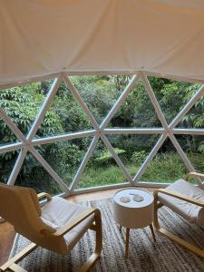 a room with a large window with chairs and a table at The Geodesic Dome in Pohara Golden Bay in Pohara