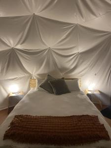 a white bed with two pillows in a tent at The Geodesic Dome in Pohara Golden Bay in Pohara