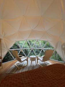 a room with a tent with two chairs and a table at The Geodesic Dome in Pohara Golden Bay in Pohara