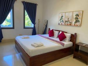 ein Schlafzimmer mit einem großen Bett mit roten Kissen in der Unterkunft Spacious Khmer Villa - Pool - Fast Wi-Fi in Phumĭ Réach Born + 113 Fotos
