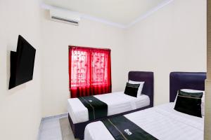 zwei Betten in einem Zimmer mit einem roten Fenster in der Unterkunft Hotel O Homestay Ka Villa Syariah in Boyolali