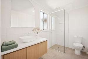 une salle de bain blanche avec un lavabo et des toilettes dans l'établissement Scarp n Sea, Sauna Views & Serene Coastal Comfort, à Falcon 31 autres photos