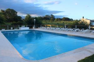 una grande piscina blu con sedie e sedie bianche di Cerro Molinos a Potrero de Garay Altre 27 foto