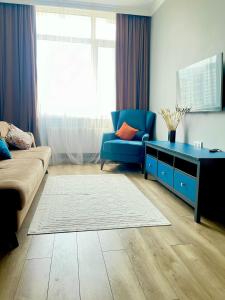 a living room with a couch and a blue chair at Новые апартаменты рядом с EXPO in Taldykolʼ