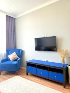 a living room with a blue chair and a flat screen tv at Новые апартаменты рядом с EXPO in Taldykolʼ +14 photos