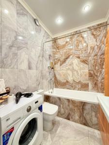 a bathroom with a washing machine and a toilet at Новые апартаменты рядом с EXPO in Taldykolʼ