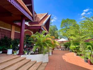eine Veranda eines Hauses mit Holztreppe und Pflanzen in der Unterkunft Spacious Khmer Villa - Pool - Fast Wi-Fi in Phumĭ Réach Born