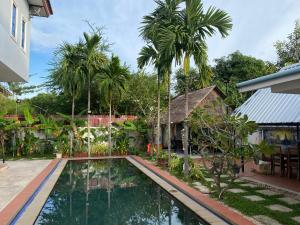einen Pool vor einem Haus mit Palmen in der Unterkunft Spacious Khmer Villa - Pool - Fast Wi-Fi in Phumĭ Réach Born
