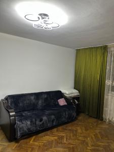 Un sofá de cuero negro en una habitación con una cortina verde en Apartament Craiova Târgul de Crăciun zona centrală, en Craiova