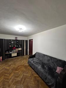 Un sofá negro en una sala de estar con suelo de madera. en Apartament Craiova Târgul de Crăciun zona centrală, en Craiova