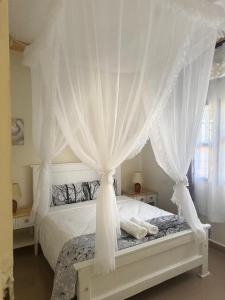 ein Schlafzimmer mit einem weißen Himmelbett und Vorhängen in der Unterkunft 41 Nile Bridge Villa in Jinja