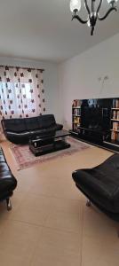 un soggiorno con mobili in pelle nera e lampadario pendente di Great 2BR Retreat for Families and Friends! a Kamëz