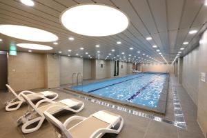 a large swimming pool with chairs in a hotel room at Seogwipo JS Hotel in Seogwipo