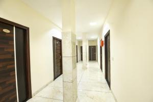 pasillo con paredes blancas, suelo de mármol y puertas negras en FabHotel Red Ark Inn, en Lāndrān