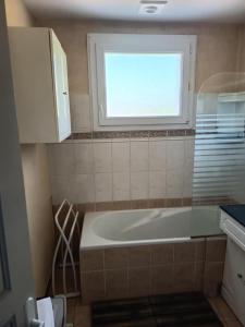 ein Badezimmer mit Badewanne und Fenster in der Unterkunft Maison 8 personnes proche Parc in Montournais + 35 Fotos