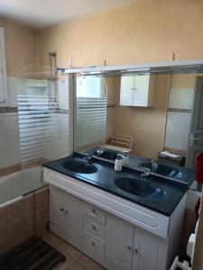 ein Badezimmer mit Waschbecken und Spiegel in der Unterkunft Maison 8 personnes proche Parc in Montournais