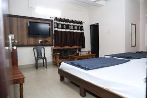 Un dormitorio con dos camas y un televisor. en Hotel Hill View, en Jamshedpur
