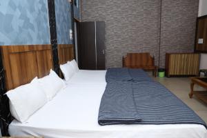 una habitación con una cama grande con sábanas y almohadas blancas en Hotel Hill View, en Jamshedpur