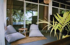 a porch with pillows and a table and a plant at Calma Cafe - Surf, Stay and Yoga in Dickwella