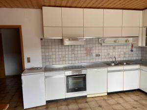 cocina con armarios blancos, fregadero y horno en Appartements Schnaittach, en Schnaittach