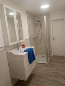 a white bathroom with a sink and a shower at Appartementhaus Brunsholm in Esgrus +74 photos