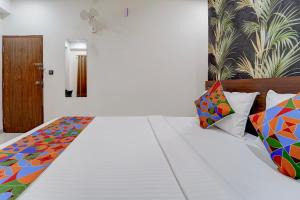 a bedroom with a bed with colorful pillows at FabHotel NRM Residency in Mysore