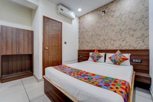 a bedroom with a bed and a wooden door at FabHotel NRM Residency in Mysore