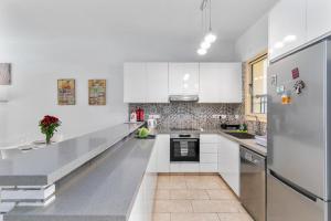 Aphrodite Gardens Apartment by Ezoria Villas في Nea Paphos: مطبخ ابيض مع دواليب بيضاء وثلاجة