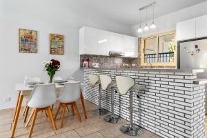 Aphrodite Gardens Apartment by Ezoria Villas في Nea Paphos: مطبخ مع طاولة وبعض الكراسي البيضاء