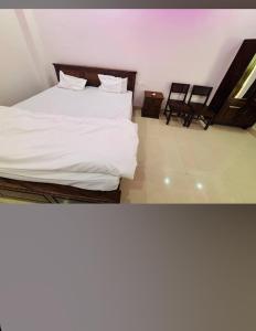 une chambre avec un lit avec des draps blancs et deux chaises dans l'établissement Hotel haveli, à Rāmgarh