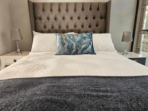 a large bed with a large headboard and two lamps at Induli on Sage in Plattekloof +16 photos