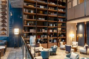 uma biblioteca com cadeiras e mesas e uma estante de livros em InterContinental Hotels Zhengzhou em Zhengzhou