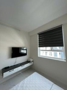 un salon avec une télévision à écran plat et une fenêtre dans l'établissement DINO Home HACOM 1BR, à Kinh Dinh