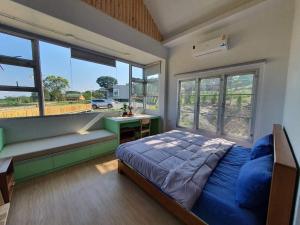 a bedroom with a bed and a desk and windows at Jacuzzi mine hills in Ban Mai