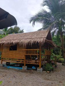 a hut with a straw roof and a palm tree at Paivana Khaosok Village in Khao Sok
