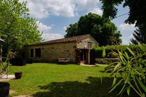 ein kleines Steinhaus in einem Hof mit grünem Rasen in der Unterkunft Maison d'hôtes in Grézels + 10 Fotos