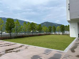 a large lawn with trees and mountains in the background at Sunshine Residence in Ayer Itam