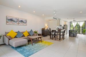 ein Wohnzimmer mit Sofa und Tisch in der Unterkunft Bangtao Beach Gardens - Apartment F22 in Ban Lum Fuang
