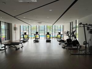 a gym with several treadmills and ellipticals in a room with windows at Sunshine Residence in Ayer Itam